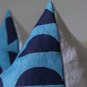 May include: Two blue and navy blue patterned throw pillows with white backing.