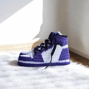 May include: Purple and white crocheted high-top slippers with black laces.