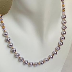 May include: A silver pearl necklace with gold beads and small purple crystals.