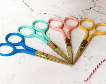 Tijeras de bordado de colores con hojas doradas.