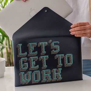 May include: A black laptop sleeve with a blue and gold embroidered design that says "Let's Get To Work".