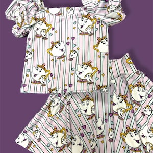 May include: A pink and white striped girls' outfit with a cartoon teapot print. The outfit includes a short-sleeved shirt with puffed sleeves and a matching skirt.
