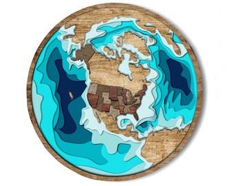 May include: A wooden wall art piece depicting a stylized map of North America with a layered ocean effect in shades of blue and turquoise.