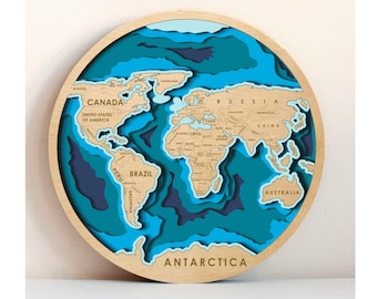 Puede incluir: Un mapa del mundo de madera con un efecto 3D en capas. Los continentes están elevados y los océanos están hundidos, creando un diseño único y visualmente atractivo. El mapa está pintado en tonos azules y marrones, con los continentes delineados en negro. El mapa está etiquetado con los nombres de los continentes y algunos de los principales países.