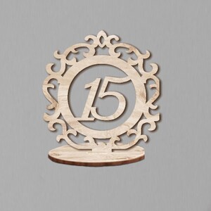 May include: Wooden table number holder with a decorative frame and the number 15 in the center.