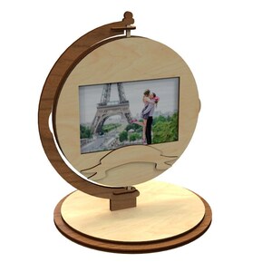 May include: A wooden photo frame shaped like a globe with a picture of a couple in front of the Eiffel Tower. The frame has a ribbon banner at the bottom.