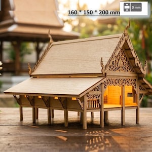May include: A light brown wooden model of a Thai-style house with intricate carved gables, a multi-tiered roof, and elevated stilts. The structure measures 160 by 150 by 200 mm with 3 mm thick panels, featuring an open interior illuminated by warm light.