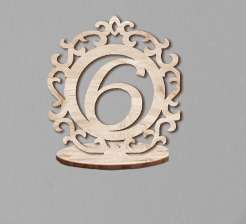 May include: Wooden table number holder with a decorative design and the number 6.