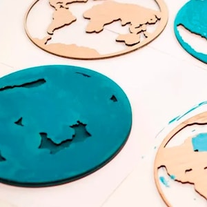 May include: A set of four wooden world map ornaments, two are painted teal blue and two are left in their natural wood color.
