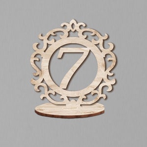 May include: A wooden table number holder with a decorative frame and the number 7 in the center.