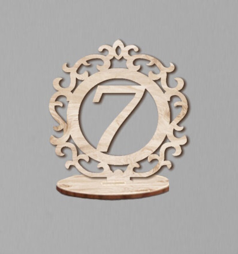 May include: A wooden table number holder with a decorative frame and the number 7 in the center.