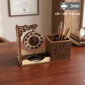 May include: A wooden desk organizer featuring a circular analog clock with Roman numerals and a square pen holder with intricate laser-cut patterns. The unit measures 230 x 100 x 160 mm with a material thickness of 3 mm, including three pens.