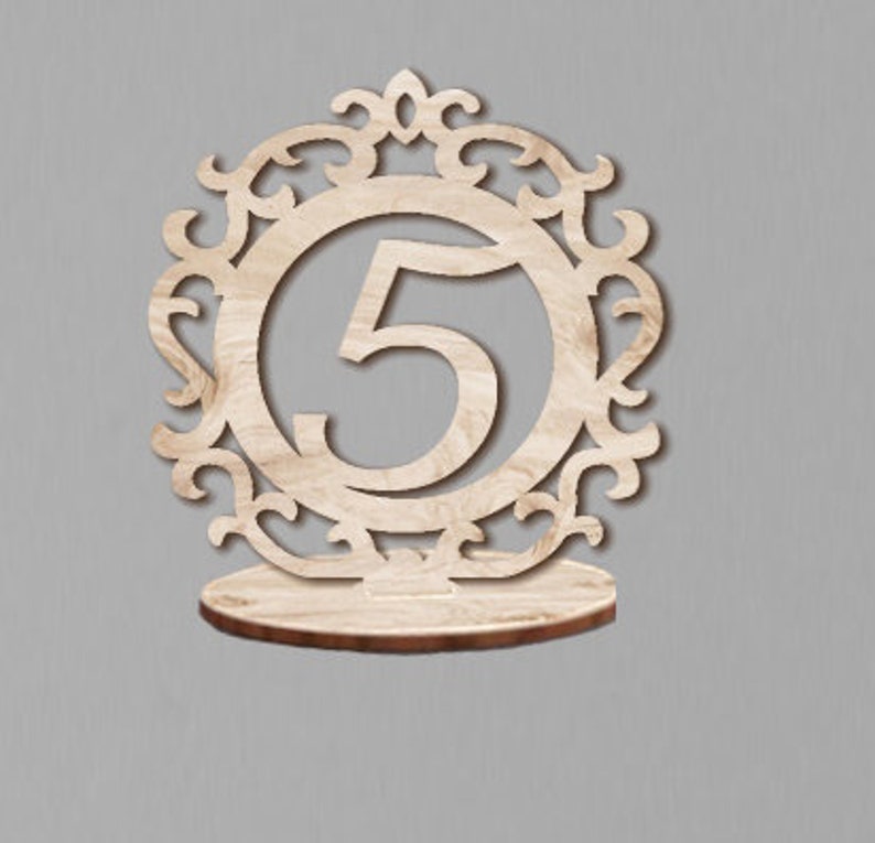 May include: Wooden table number holder with a decorative design and the number 5.