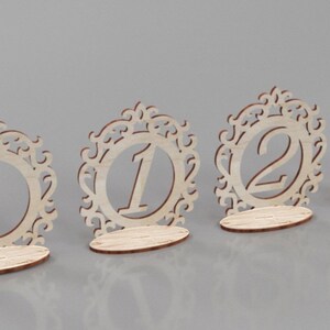 May include: Four wooden table number holders with ornate designs. The numbers 1, 2, and 3 are visible.