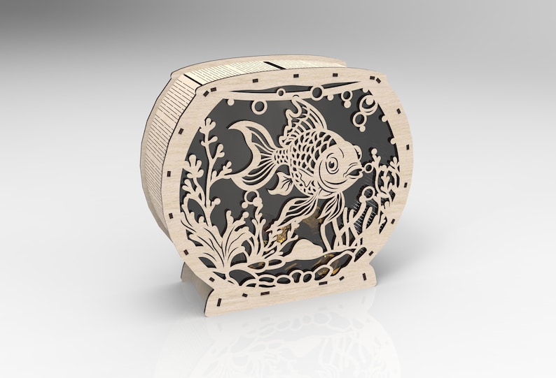 May include: A wooden cutout of a fishbowl with a goldfish inside. The fishbowl is decorated with seaweed and bubbles. The cutout is made of light brown wood and has a black background.