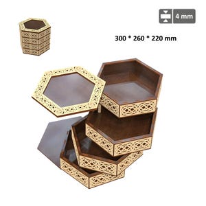 Peut inclure: Ensemble de plateaux de rangement hexagonaux en bois avec des motifs décoratifs découpés. Les plateaux sont empilés, révélant leurs différentes profondeurs et leurs motifs complexes. Dimensions : 30 x 26 x 22 cm, épaisseur 4 mm.