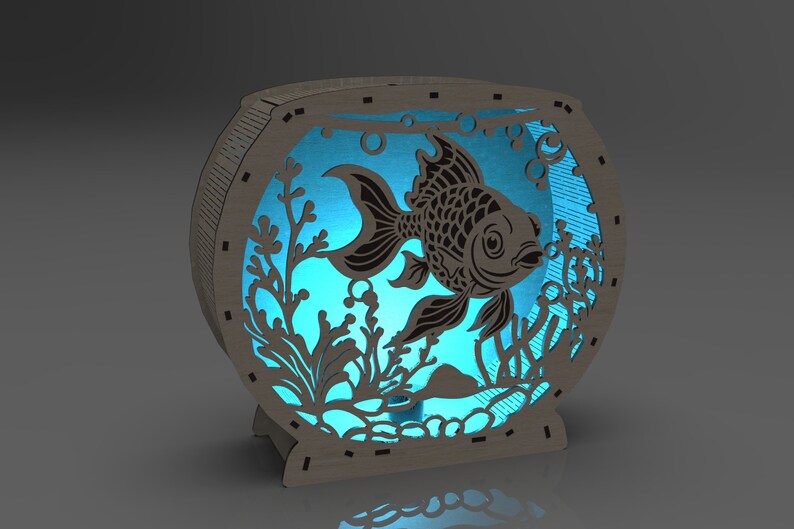 May include: A wooden fishbowl nightlight with a blue light shining through the cutout design of a fish and seaweed.