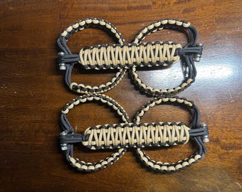 May include: Four black and tan paracord door handles with silver beads. The handles are braided in a pattern and are designed to be used as a replacement for standard door handles.
