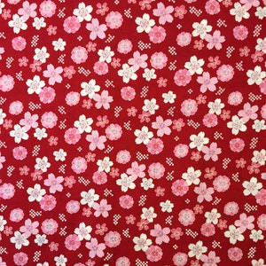 Puede incluir: Tela roja con un patrón repetido de flores de cerezo blancas y rosas. La tela tiene una textura sutil.