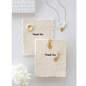 Fotografia minimalista di collana/orecchini, carta con bordo peloso, sfondo di accessori per fotografia di unghie/gioielli, ornamento decorativo, carta color crema