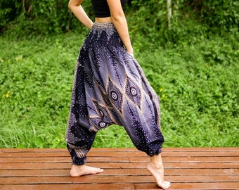 Puede incluir: Una mujer con un top negro de tirantes y un pantalón de harén estampado en negro y plata con un diseño de plumas de pavo real.