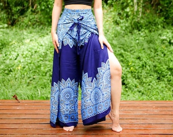 May include: A woman wearing a black crop top and blue and silver patterned trousers with a side slit. The trousers have a tie at the waist.