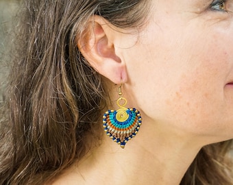 May include: A pair of gold-toned earrings with a heart-shaped design. The earrings are made of small blue, orange, and brown beads.
