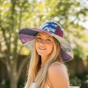 Puede incluir: Un sombrero de sol de ala ancha con un diseño de patchwork. El sombrero presenta paneles de telas azules, moradas y estampadas. El sombrero se usa al aire libre, con un fondo verde borroso.