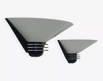 May include: Two wall sconces with a geometric design. The sconces have a light gray, triangular shade, a black base, and horizontal silver bars. The sconces are of different sizes.
