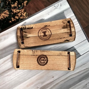 May include: Two wooden serving trays made from reclaimed wood. One tray features the "ILLINOIS FIGHTING ILLINI" logo, and the other displays the "CUBS" logo. Both trays have metal handles and are designed for serving food or drinks.