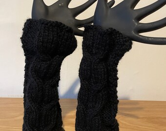 May include: A pair of black knitted arm warmers with a cable knit pattern.