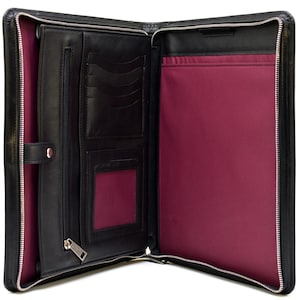 May include: A black leather portfolio case with a silver zipper closure, featuring a deep magenta interior lining. The left side includes multiple card slots, a clear ID window, and a zippered pocket, while the right side has a large document sleeve.