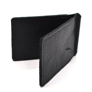 Puede incluir: Un clip para billetes de cuero negro con una superficie texturizada y granulada. La cartera est&aacute; construida con dos paneles rectangulares unidos por un lomo central, dise&ntilde;ados para sujetar billetes entre las secciones de cuero plegadas.