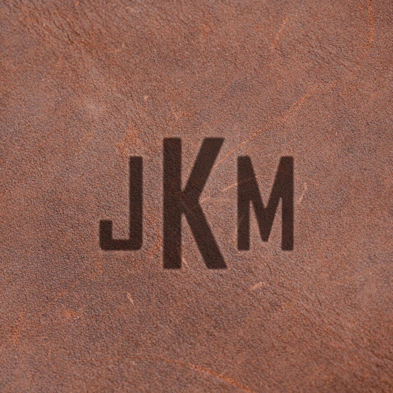 a close-up of a brown leather surface with the initials "JKM" prominently displayed in the center.