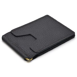 Puede incluir: Una cartera con clip para dinero de cuero texturizado en color marr&oacute;n oscuro, con forma rectangular y una ranura central para tarjetas. La cartera incluye un mecanismo de clip met&aacute;lico dorado en el borde inferior para sujetar billetes.