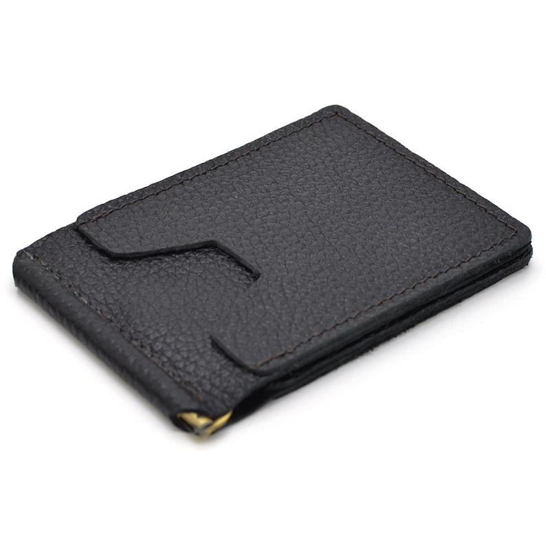 Puede incluir: Una cartera con clip para dinero de cuero texturizado en color marr&oacute;n oscuro, con forma rectangular y una ranura central para tarjetas. La cartera incluye un mecanismo de clip met&aacute;lico dorado en el borde inferior para sujetar billetes.