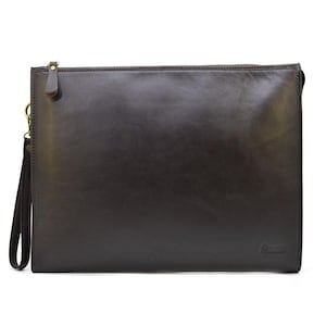 May include: A dark brown leather clutch with a zipper closure and a wrist strap. The rectangular bag has a smooth surface and a gold-colored zipper pull. The wrist strap is attached with a gold-colored clasp.