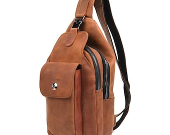 May include: A brown leather sling bag with a front pocket and two zippered compartments. The bag has a black strap and a metal buckle. The leather has a distressed look.