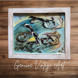 Puede incluir: Obra de arte vintage enmarcada con un diseño abstracto surrealista en tonos azules, amarillos y marrones. La obra está firmada y enmarcada en un marco de madera blanqueada. El texto "Genuine Vintage Art" está escrito en cursiva en la parte inferior.