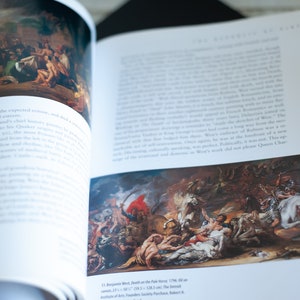 May include: Open book with a detailed painting of a battle scene, featuring figures on horseback and fallen soldiers. The artwork is vibrant with reds, whites, and browns. Text on the page describes the painting and its artist.