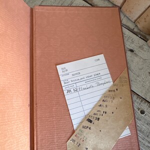 Puede incluir: Libro vintage abierto con una cubierta y p&aacute;ginas de color salm&oacute;n. Una tarjeta de biblioteca est&aacute; metida dentro, con el t&iacute;tulo "Dear Brutus, and other plays" y la fecha "JUL 12". El lomo del libro es visible y las p&aacute;ginas est&aacute;n envejecidas.