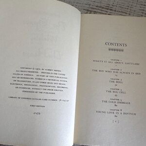 May include: A book titled "What's It All About, Gottlieb?" by Aubrey Menen. The book cover is white with black text. The book is open to the contents page, which lists the chapters and page numbers.