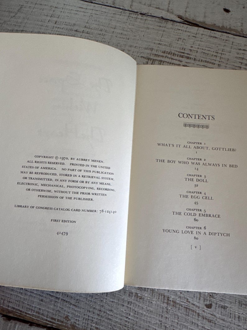 May include: A book titled "What's It All About, Gottlieb?" by Aubrey Menen. The book cover is white with black text. The book is open to the contents page, which lists the chapters and page numbers.