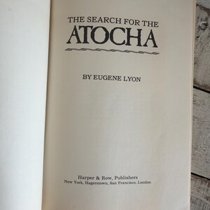 May include: An open book displaying the title "THE SEARCH FOR THE ATOCHA" in black lettering. The author's name, Eugene Lyon, is below the title. The publisher's name, Harper & Row, is at the bottom.