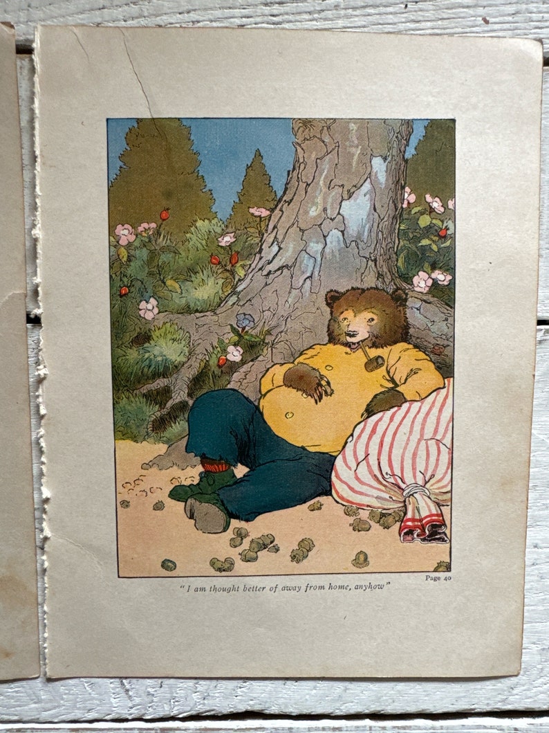 May include: A cartoon illustration of a bear wearing a yellow shirt and blue pants sitting under a tree with a striped bag. The bear is holding a pipe in its mouth and has a thoughtful expression on its face. The text "I am thought better of away from home, anyhow" is printed below the image.