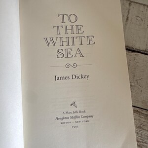 Pu&ograve; includere: Pagina di libro aperta con il titolo "TO THE WHITE SEA" di James Dickey. L'editore &egrave; Houghton Mifflin Company, con copyright del 1993. Il testo &egrave; in un carattere serif su una pagina color crema.