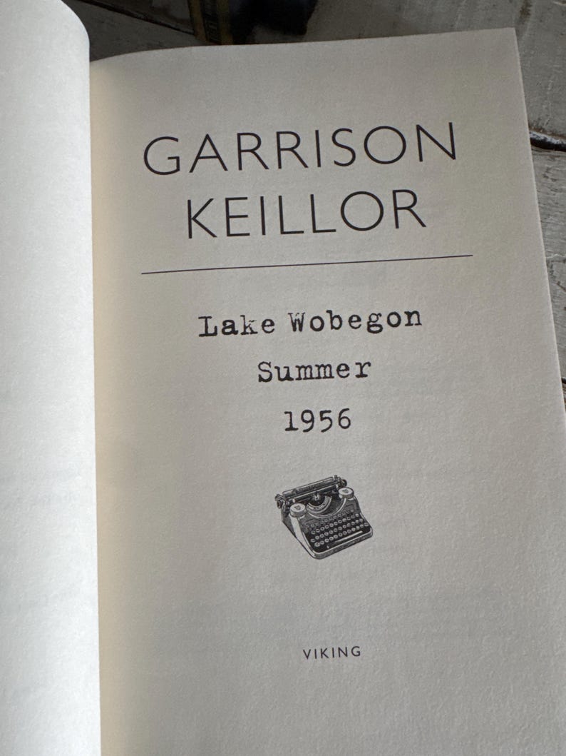 May include: Open book page with the title "Garrison Keillor" above "Lake Wobegon Summer 1956." A small illustration of a vintage typewriter is below the text. The publisher's name, "VIKING," is at the bottom.