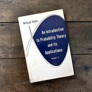 Peut inclure: Livre à couverture blanche avec un titre en anglais : "An Introduction to Probability Theory and its Applications" de William Feller. Un ovale bleu foncé contient le titre en blanc. Volume II.