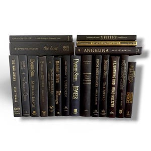 May include: A collection of hardcover books with dark covers, arranged in stacks and rows. Titles and authors are visible, with gold lettering on some spines. The books vary in size and include titles like "The Host" and "Angelina".