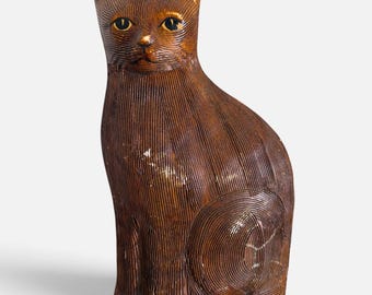 May include: A brown cat figurine with a textured, ribbed surface throughout its body. The cat is in a seated position with its head facing forward, featuring yellow eyes with black pupils and subtle gold-toned highlights on the ears and face.